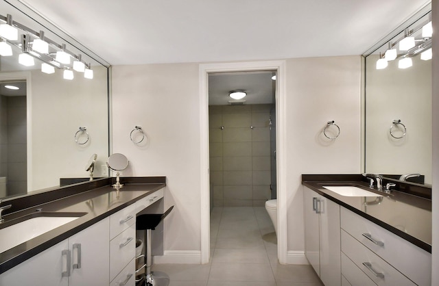 bathroom featuring tile patterned flooring, vanity, a tile shower, and toilet