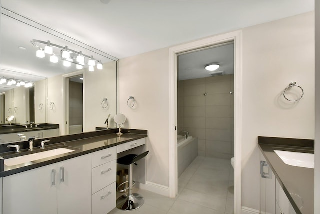 bathroom with vanity, toilet, tile patterned flooring, and tiled tub