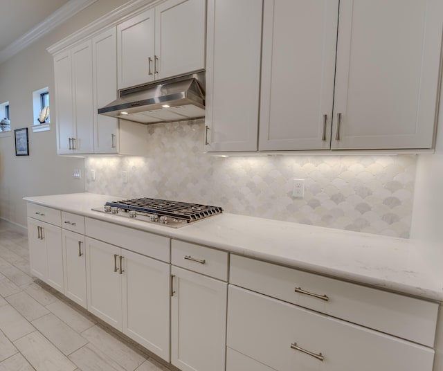 kitchen with crown molding, decorative backsplash, light stone countertops, white cabinetry, and stainless steel gas cooktop