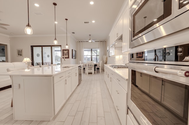 kitchen with a spacious island, sink, decorative light fixtures, white cabinetry, and stainless steel appliances