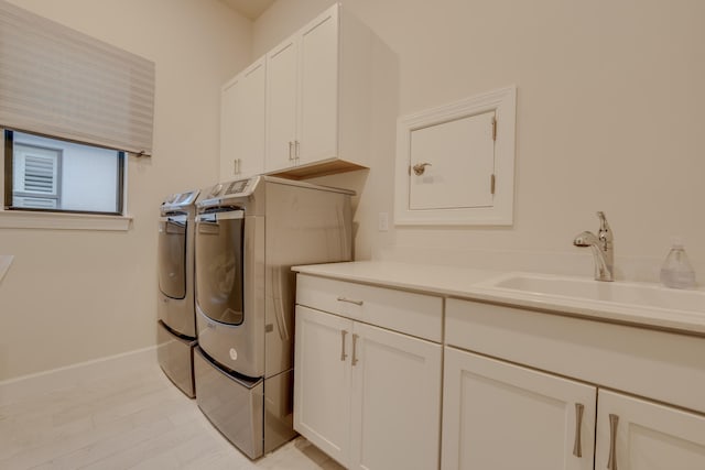 clothes washing area featuring cabinets, washer and clothes dryer, and sink