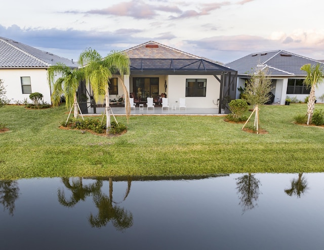 back house at dusk with a lanai, a patio area, and a water view