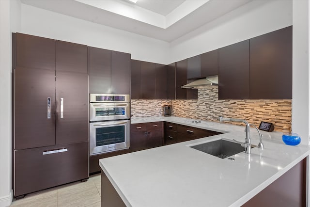 kitchen with sink, dark brown cabinetry, stainless steel double oven, kitchen peninsula, and extractor fan