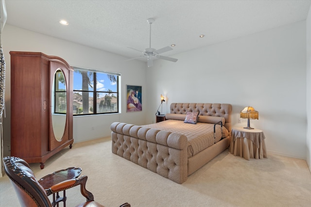 bedroom featuring ceiling fan, light colored carpet, and a textured ceiling