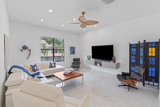 living room featuring ceiling fan and a textured ceiling