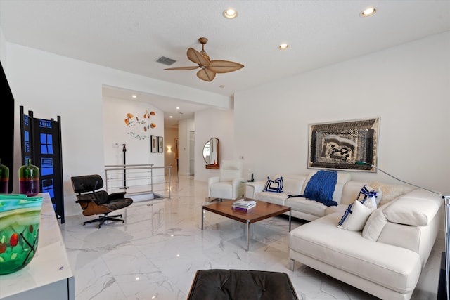 living room with ceiling fan and a textured ceiling