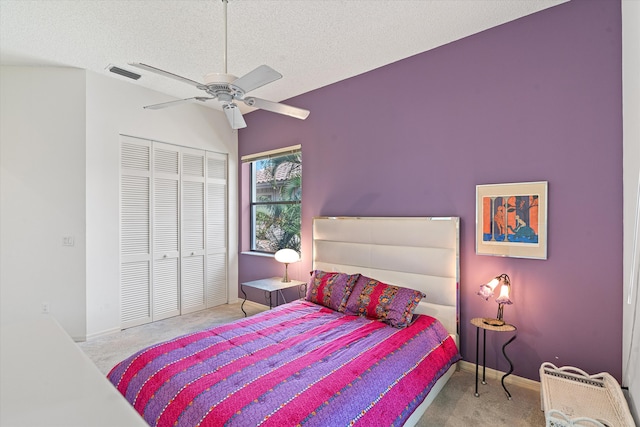 bedroom featuring ceiling fan, light colored carpet, a textured ceiling, and a closet