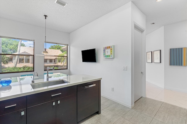 kitchen with pendant lighting, a textured ceiling, and sink