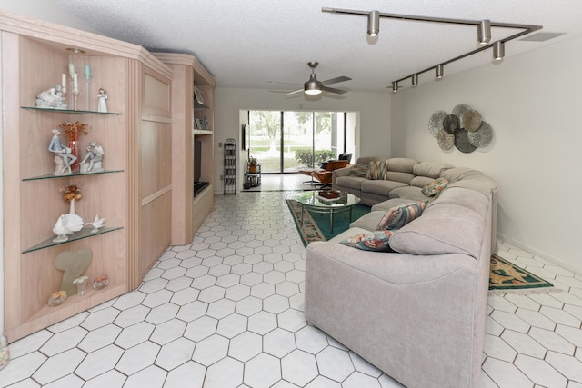 living room featuring rail lighting, ceiling fan, and a textured ceiling