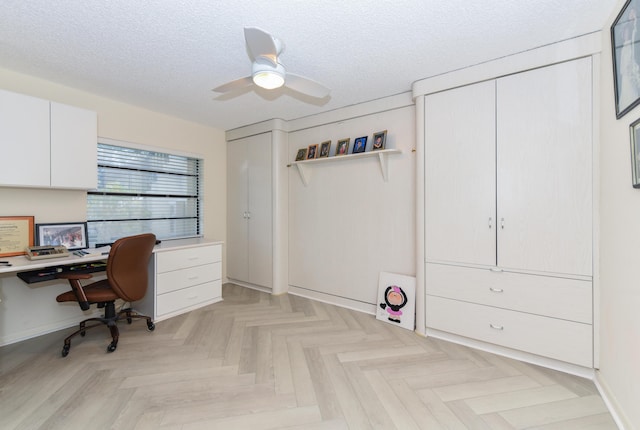 office area featuring a textured ceiling, light parquet floors, ceiling fan, and built in desk