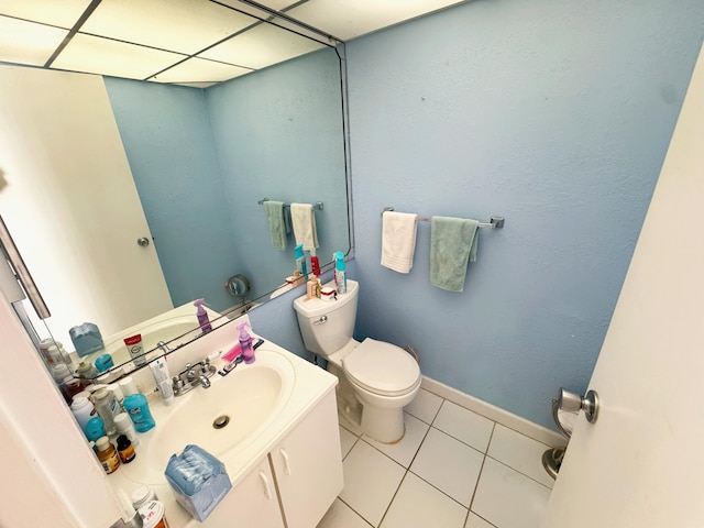 bathroom featuring tile patterned flooring, vanity, a drop ceiling, and toilet