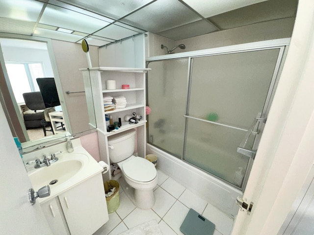 full bathroom with a paneled ceiling, tile patterned floors, vanity, shower / bath combination with glass door, and toilet