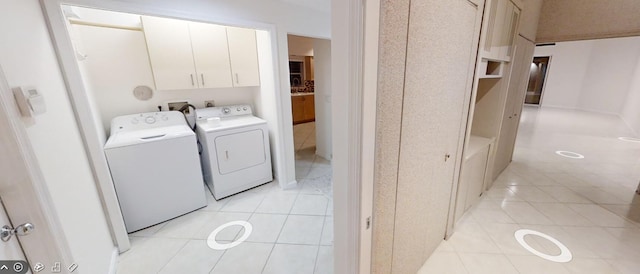 laundry area with cabinets, light tile patterned floors, and washer and clothes dryer