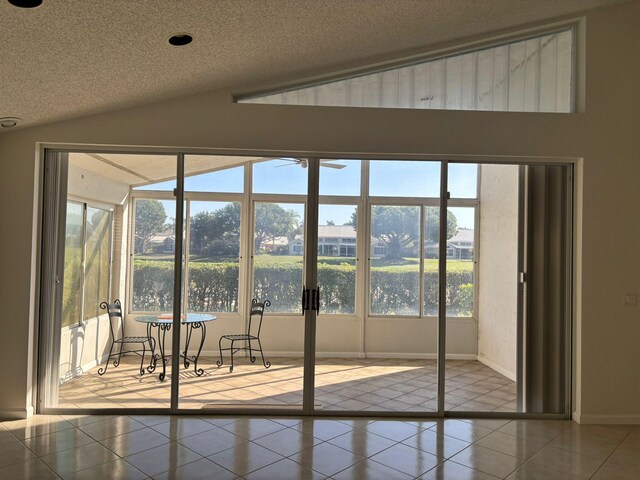 doorway to outside featuring plenty of natural light, a water view, a textured ceiling, and vaulted ceiling