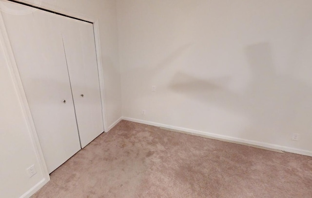 unfurnished bedroom with light carpet and a closet