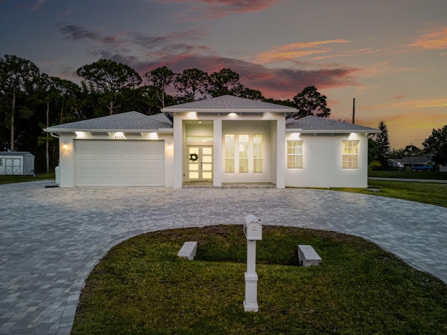 prairie-style house featuring a front yard, stucco siding, french doors, decorative driveway, and a garage