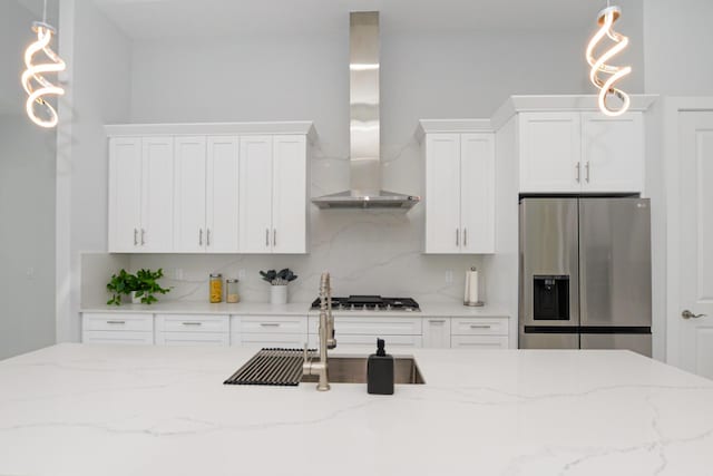 kitchen featuring wall chimney range hood, white cabinets, backsplash, and stainless steel appliances