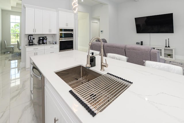 kitchen with a breakfast bar, appliances with stainless steel finishes, light stone countertops, and white cabinets