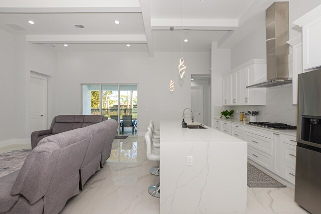 kitchen featuring a sink, open floor plan, appliances with stainless steel finishes, wall chimney range hood, and marble finish floor