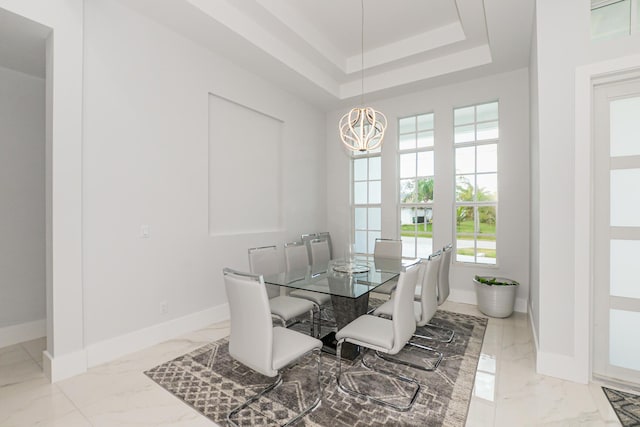 dining area featuring a raised ceiling and a chandelier