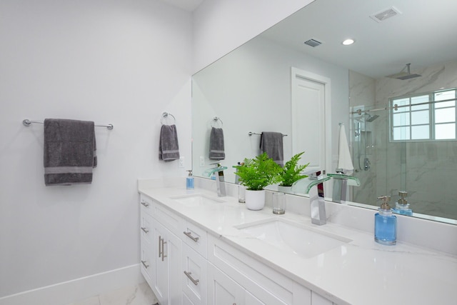 full bathroom with double vanity, a marble finish shower, and a sink