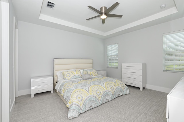 carpeted bedroom featuring ceiling fan and a tray ceiling