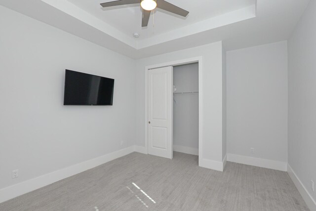 unfurnished bedroom featuring a raised ceiling, baseboards, and carpet floors