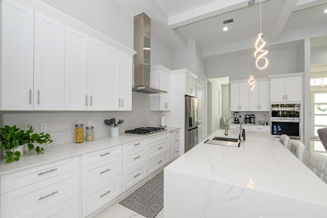 kitchen with pendant lighting, sink, stainless steel appliances, a kitchen breakfast bar, and wall chimney exhaust hood