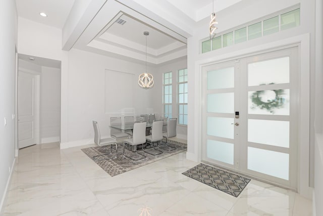 foyer with a tray ceiling and french doors