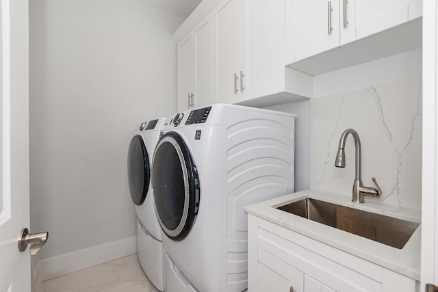 clothes washing area featuring cabinets, washing machine and dryer, and sink