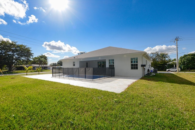 rear view of property featuring roof with shingles, stucco siding, cooling unit, a yard, and a patio