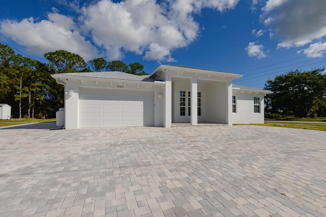 view of front facade with stucco siding, decorative driveway, and a garage