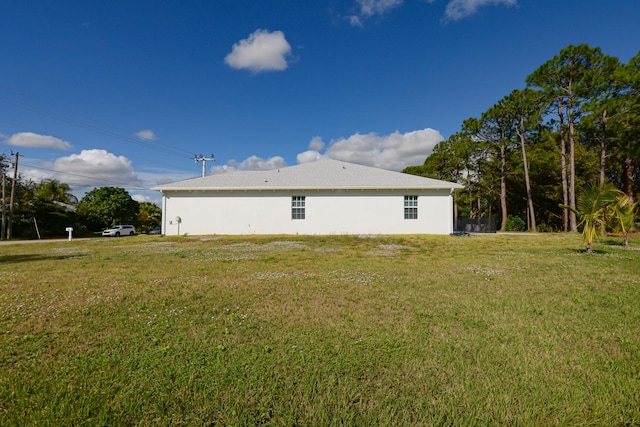 back of property with a yard and stucco siding