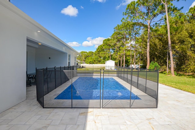 view of swimming pool with a storage unit, an outbuilding, a fenced backyard, and a patio area