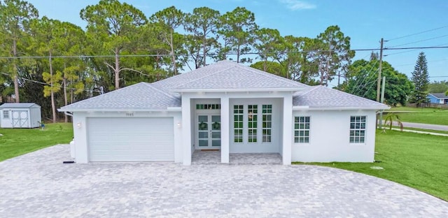 exterior space featuring a front lawn, roof with shingles, decorative driveway, a garage, and an outdoor structure