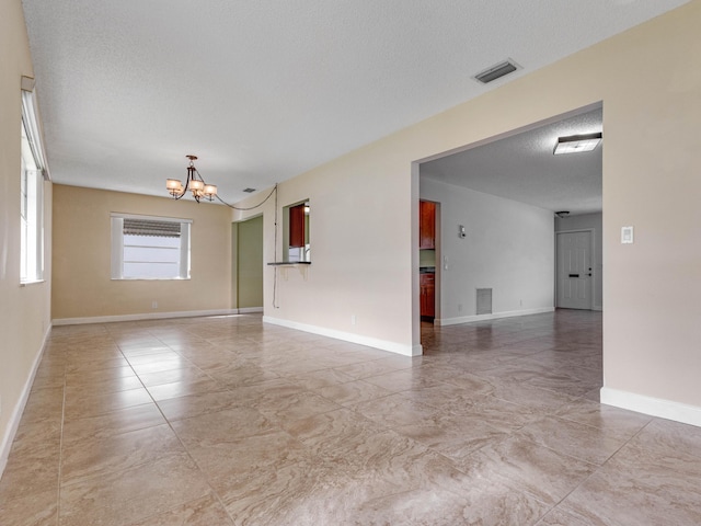 unfurnished room featuring a chandelier and a textured ceiling