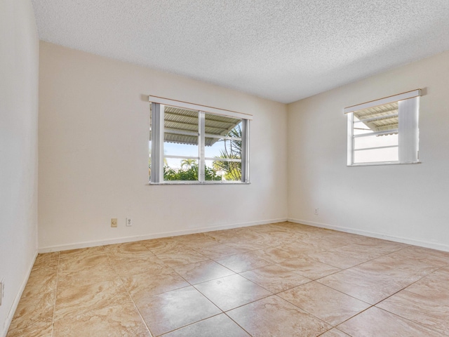 tiled spare room with a textured ceiling and a healthy amount of sunlight