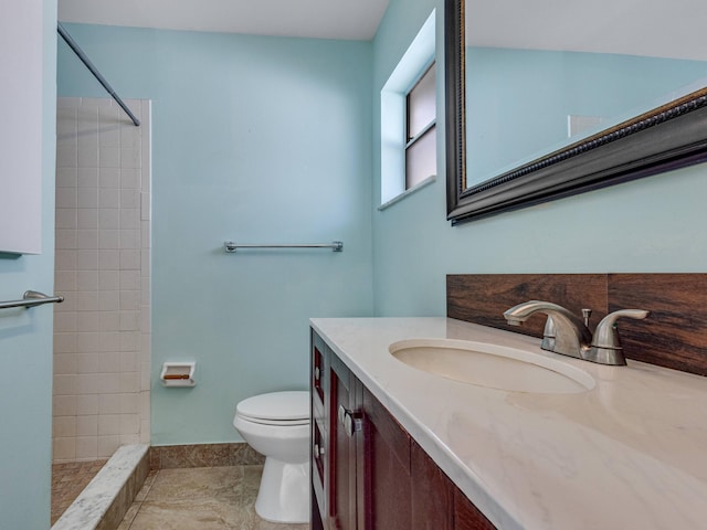 bathroom with tile patterned floors, vanity, toilet, and a tile shower