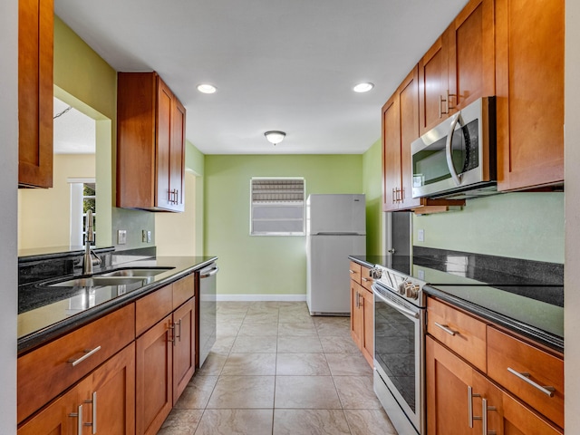 kitchen featuring light tile patterned floors, stainless steel appliances, dark stone counters, and sink