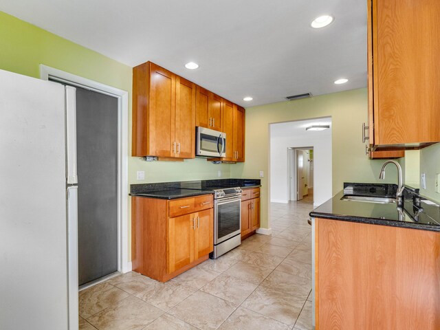 kitchen featuring dark stone countertops, sink, and appliances with stainless steel finishes