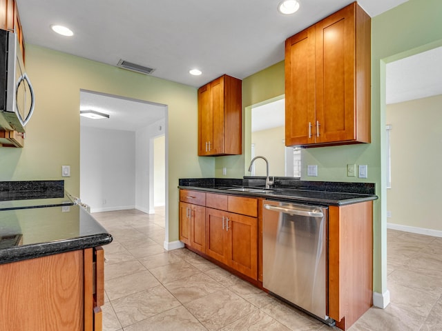 kitchen with stainless steel appliances, dark stone countertops, and sink