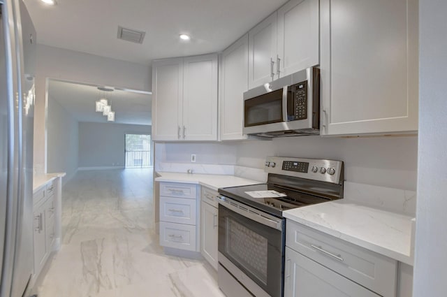 kitchen featuring light stone countertops, appliances with stainless steel finishes, white cabinetry, and pendant lighting