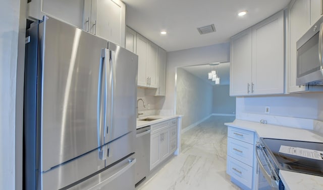 kitchen featuring light stone countertops, decorative light fixtures, stainless steel appliances, and sink