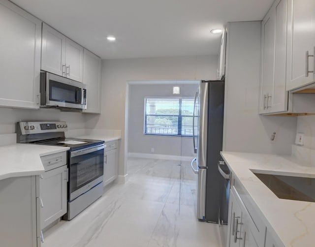 kitchen featuring white cabinetry, light stone countertops, sink, and appliances with stainless steel finishes