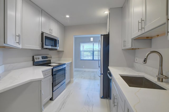 kitchen featuring white cabinetry, sink, light stone countertops, and appliances with stainless steel finishes