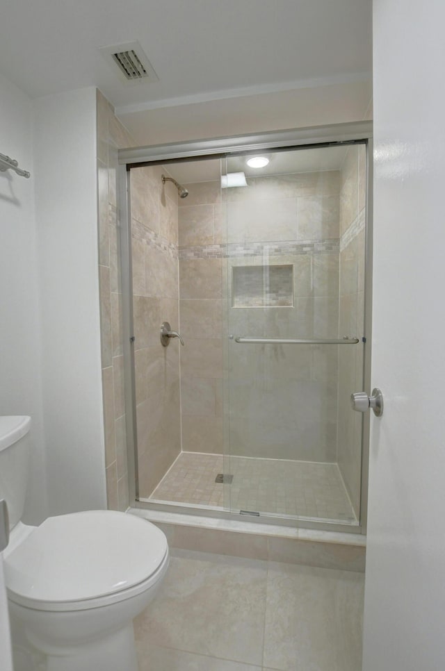 bathroom featuring tile patterned flooring, toilet, and walk in shower