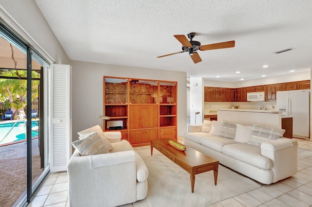 tiled living room featuring ceiling fan, sink, and a textured ceiling