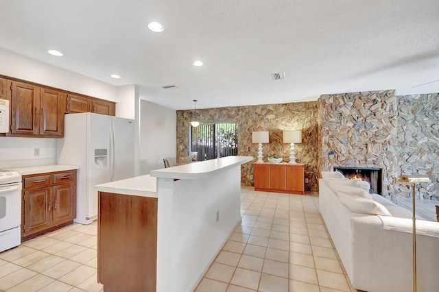 kitchen with pendant lighting, a center island, white appliances, a stone fireplace, and light tile patterned flooring