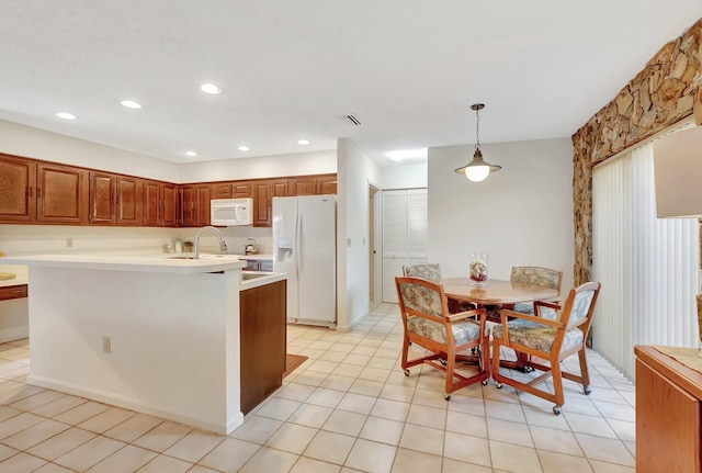 kitchen with light tile patterned floors, hanging light fixtures, and white appliances