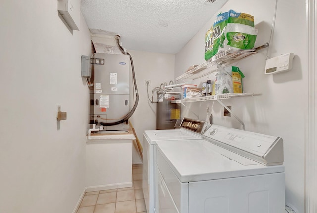 clothes washing area featuring electric water heater, independent washer and dryer, heating unit, a textured ceiling, and light tile patterned floors